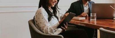 Two workers at conference table, one writing on tablet, Intelligent Collaboration | DXC Technology Insights